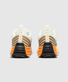 Rear view of athletic sneakers with orange ribbed soles and beige striped uppers