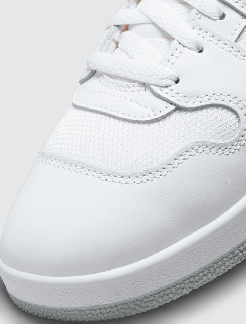 Close-up of a white sneaker with textured mesh and leather upper, white laces, and rubber sole