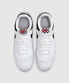 Top view of white low-top sneakers with black accents and checkerboard tongue label