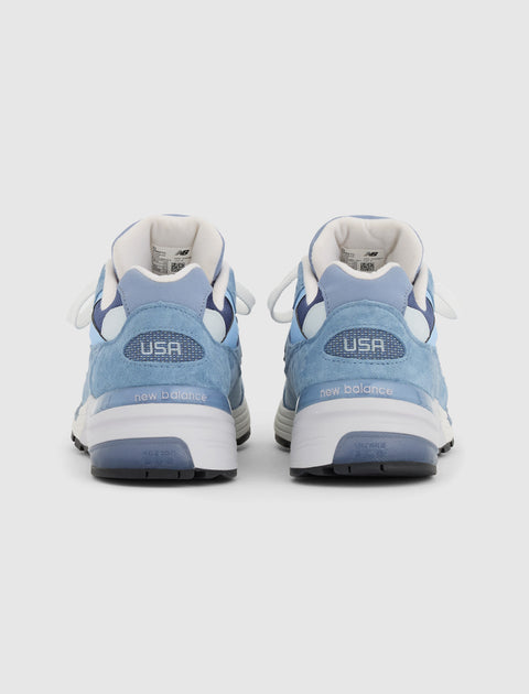 Back view of light blue New Balance sneakers with USA detail and white midsoles