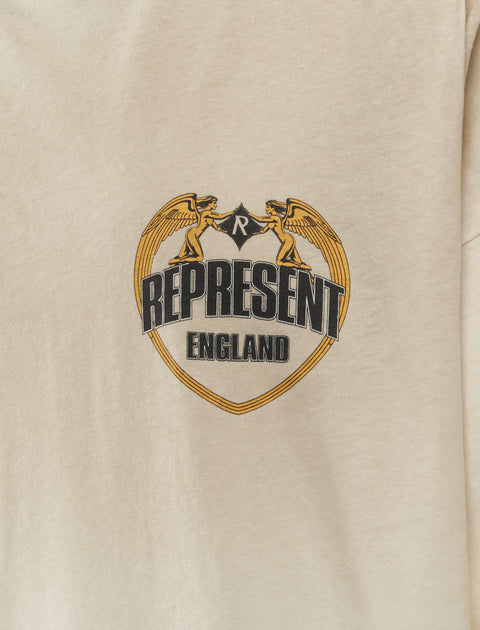 Beige streetwear t-shirt with crest graphic, angel figures, and 'REPRESENT ENGLAND' text