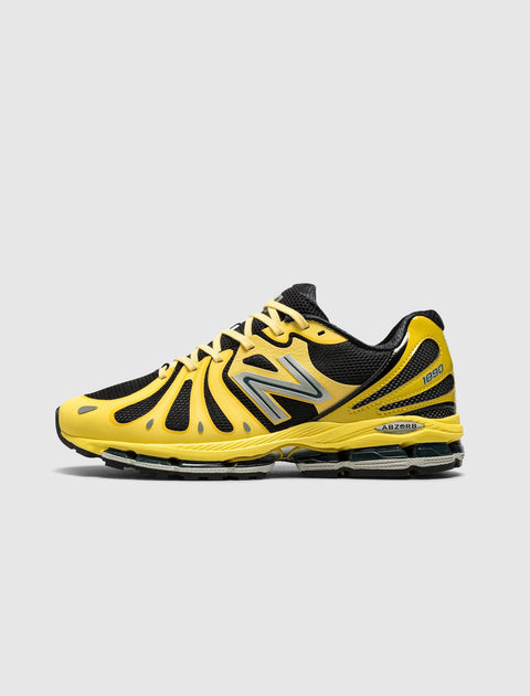 Yellow and black athletic sneaker with mesh panels, side logo, and cushioned sole on white background