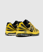 Yellow and black athletic sneakers with mesh panels and chunky sole, rear angle view
