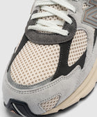 Close-up of beige and grey mesh and suede sneaker with white laces and textured sole