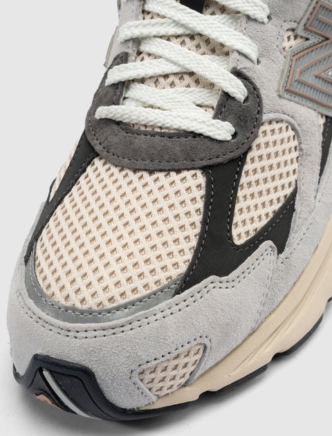 Close-up of beige and grey mesh and suede sneaker with white laces and textured sole