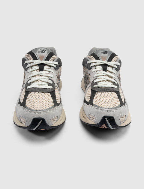 Pair of grey and beige mesh sneakers with white laces, front view on white background
