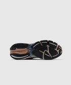 Closeup of black and brown running shoe sole with New Balance logo on white background
