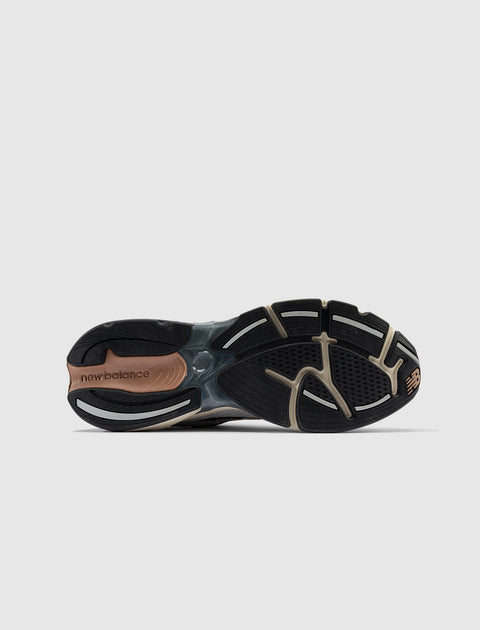 Closeup of black and brown running shoe sole with New Balance logo on white background