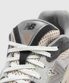 Close-up of grey mesh and suede sneaker with white laces and embroidered logo