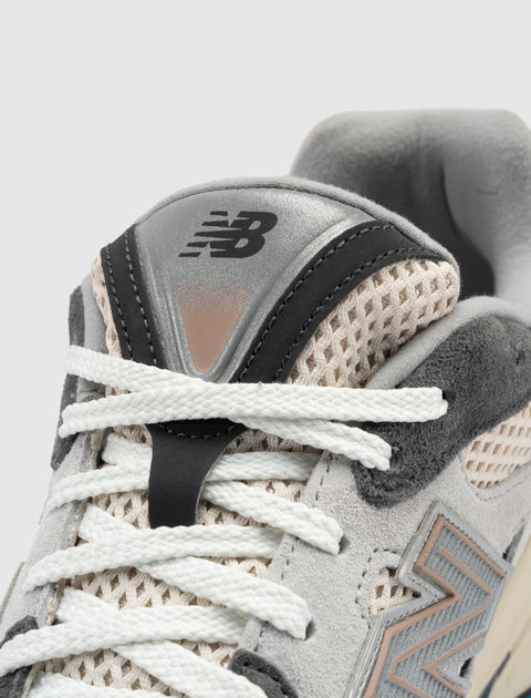 Close-up of grey mesh and suede sneaker with white laces and embroidered logo