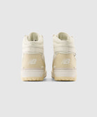 Rear view of beige high-top New Balance sneakers on a plain background