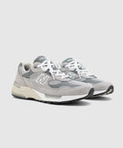 Men's grey athletic sneakers with suede and mesh panels, white laces, and cushioned soles.