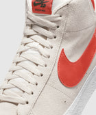 Close-up of white suede high-top sneaker with red Swoosh and label on tongue