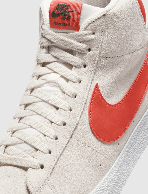 Close-up of white suede high-top sneaker with red Swoosh and label on tongue