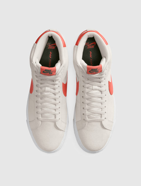 Top view of white suede high-top sneakers with orange Swoosh accents and laces