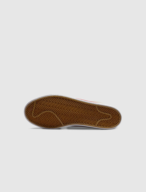 Gum sole detail of a streetwear sneaker with herringbone tread on grey background