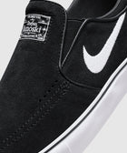 Black slip-on skate shoe with white swoosh logo, suede upper, and white rubber sole
