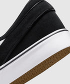 Close-up of black suede slip-on sneaker with white sole and gum outsole