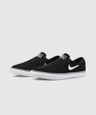 Black and white slip-on skate shoes with suede upper and white rubber sole on plain background