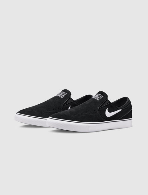 Black and white slip-on skate shoes with suede upper and white rubber sole on plain background