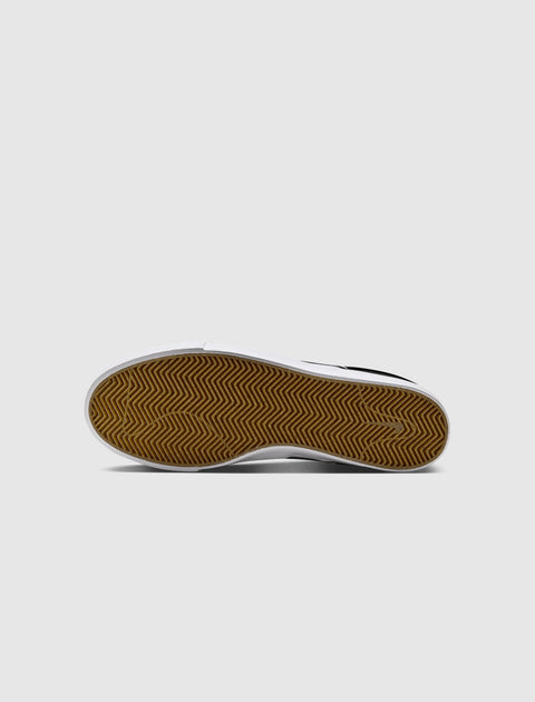 Black and white slip-on sneaker showing brown gum sole with herringbone tread pattern