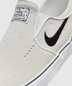 White suede slip-on skate shoe with black swoosh logo and label on tongue