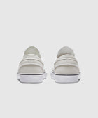 Rear view of white slip-on sneakers with white soles on a plain background