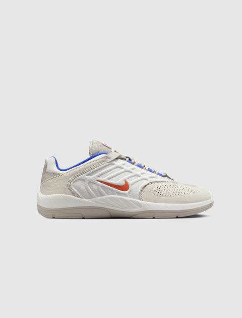 White and beige low-top sneaker with orange Swoosh and blue trim on a plain background
