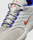 White and gray sneaker with orange swoosh, blue eyelets, and mesh texture detail