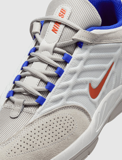 White and gray sneaker with orange swoosh, blue eyelets, and mesh texture detail