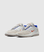 White and beige low-top sneakers with blue lining and orange swoosh logo on side