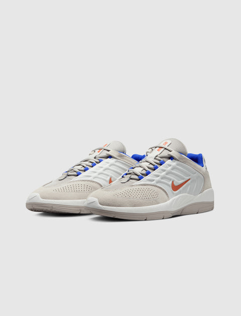 White and beige low-top sneakers with blue lining and orange swoosh logo on side