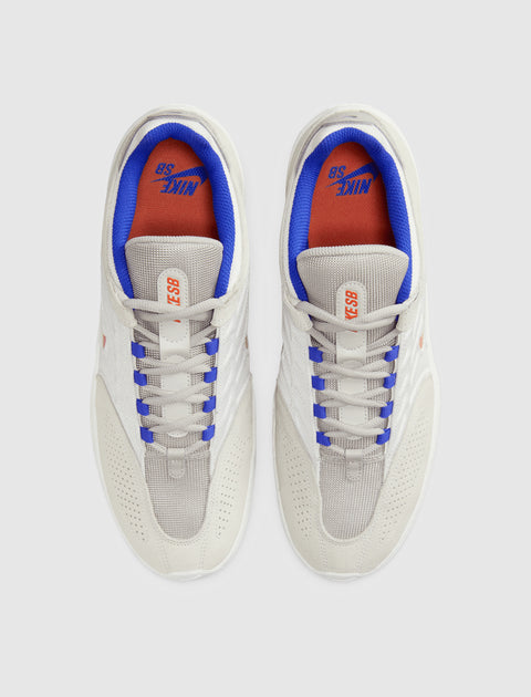 White and grey low-top sneakers with blue and orange accents, viewed from above