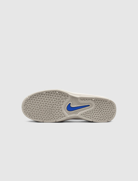 White sneaker sole with textured pattern and blue swoosh logo on a neutral background