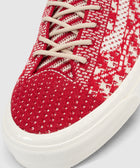 Close-up of red and white knit textured sneaker with beige laces and white sole