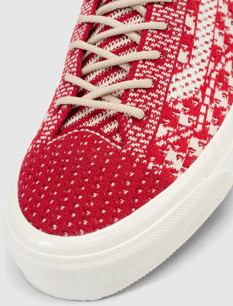 Close-up of red and white knit textured sneaker with beige laces and white sole