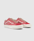 Red and white low-top sneakers with woven pattern, beige laces, and white sole