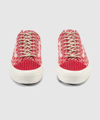 Pair of red and white patterned low-top sneakers with beige laces on a light background