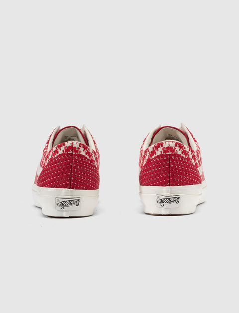 Back view of red and white patterned low-top sneakers with white soles on gray background