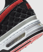 Close-up of a black and red sneaker with hexagonal detailing and visible air cushioning.