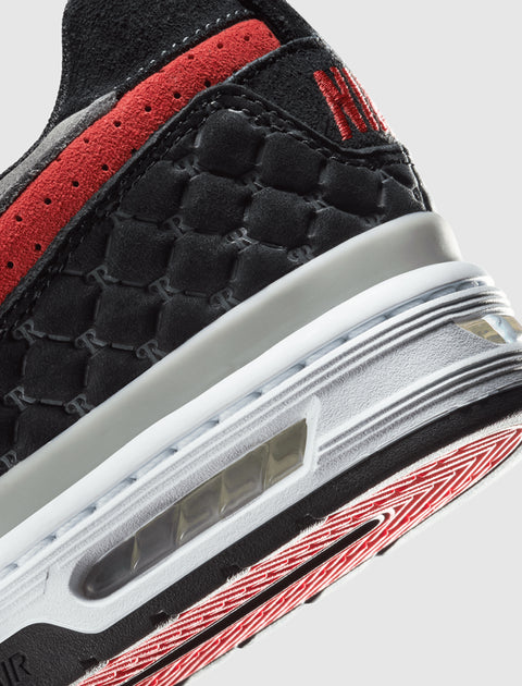 Close-up of a black and red sneaker with hexagonal detailing and visible air cushioning.