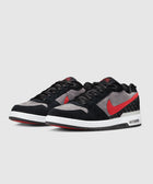 Pair of low-top sneakers with black, grey, and red suede panels, white midsole, and black laces