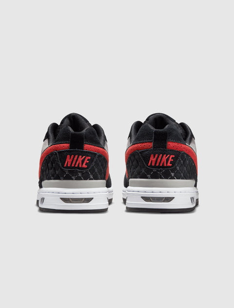 Back view of black and red Nike low-top sneakers with white soles on gray background
