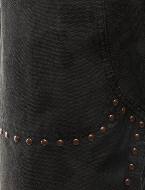 Close-up of black denim fabric with bronze rivets and subtle camouflage pattern