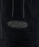 Black nylon streetwear jacket pocket with bold Pleasures logo and reflective trim detail