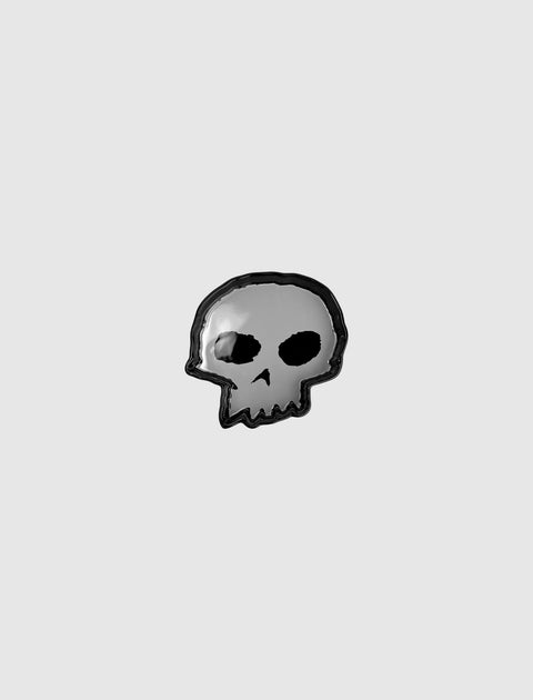 Black and gray enamel skull pin on a plain light background