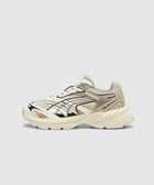 Beige and cream athletic sneaker with black graphic details, side branding, and chunky sole.