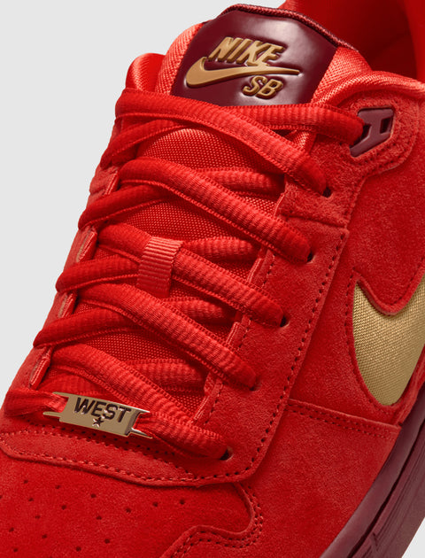 Red Nike SB sneaker close-up with gold swoosh, gold logo, and 'WEST' lace tag