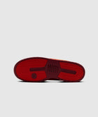 Red sneaker sole with textured grip and basketball logo, streetwear footwear