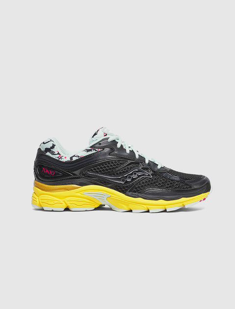 Black mesh sneaker with yellow sole, light blue laces, and Tokyo text on the heel